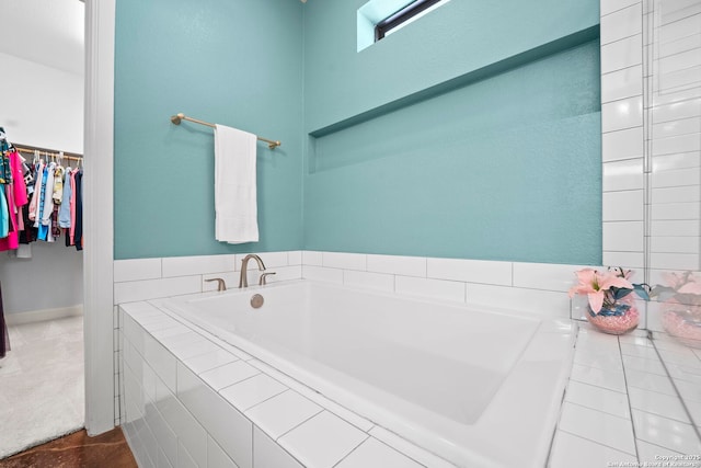 bathroom with a garden tub and a spacious closet