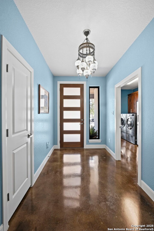 foyer with baseboards, an inviting chandelier, separate washer and dryer, finished concrete floors, and a textured wall