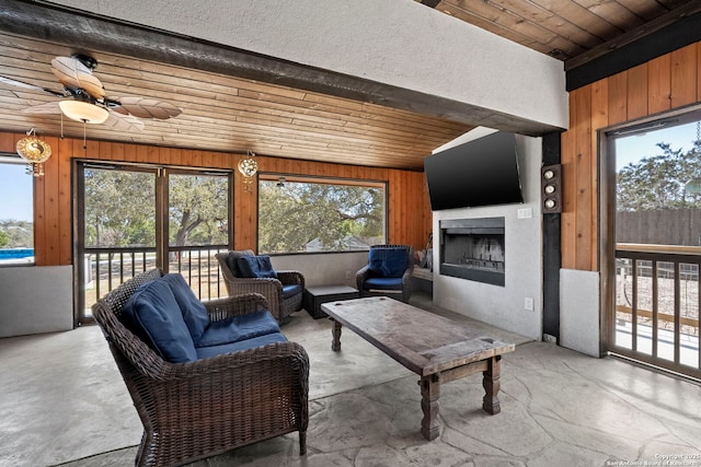 living area featuring concrete floors, wooden walls, wood ceiling, and a fireplace