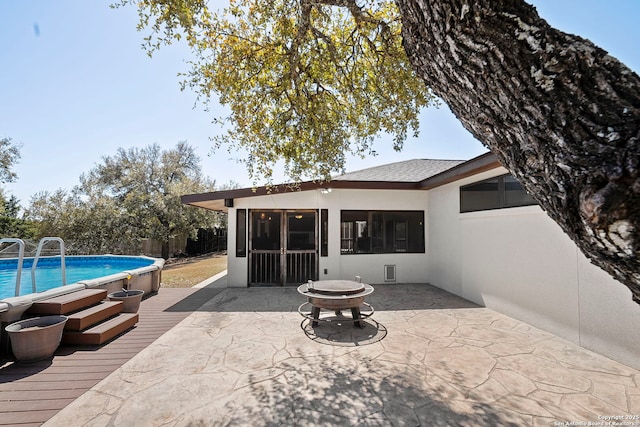 pool featuring a patio, a fire pit, a sunroom, and fence