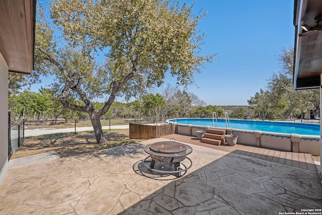 view of patio / terrace with an outdoor pool, fence, and an outdoor fire pit