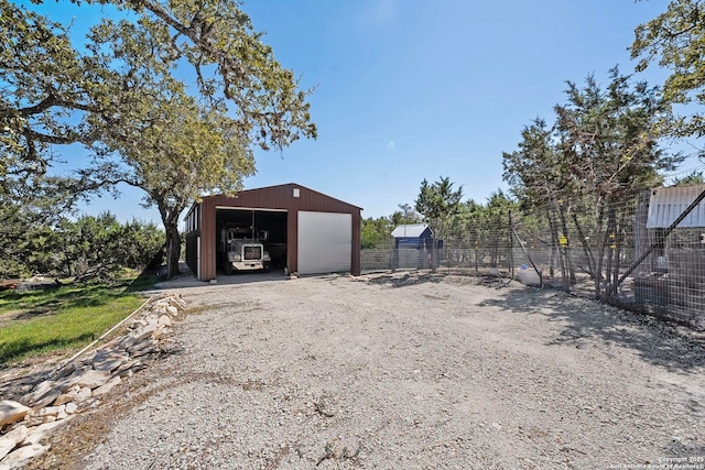 view of pole building featuring gravel driveway and fence