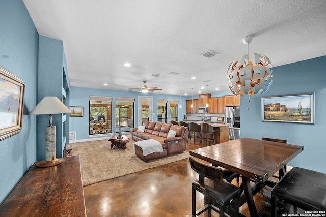 dining space with visible vents, finished concrete flooring, recessed lighting, ceiling fan with notable chandelier, and a textured ceiling