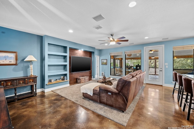 living room with built in shelves, concrete flooring, and baseboards