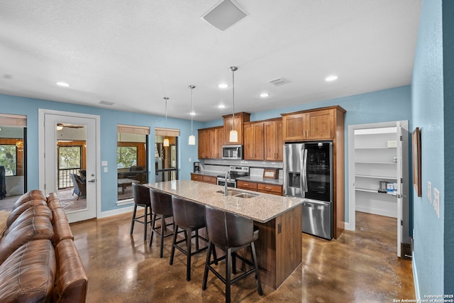 kitchen featuring brown cabinets, a sink, finished concrete flooring, stainless steel appliances, and baseboards