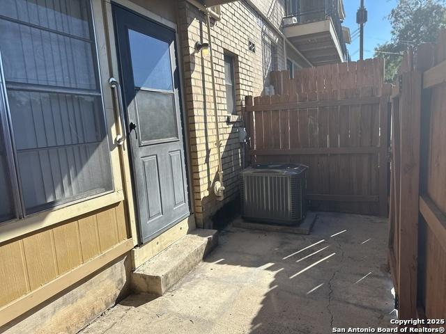 view of home's exterior with entry steps, brick siding, fence, and central air condition unit