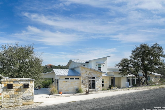 modern home featuring stone siding, a standing seam roof, metal roof, and stucco siding