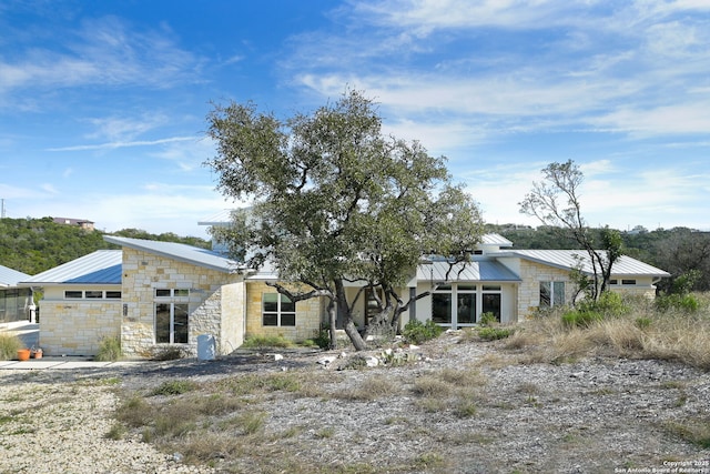 view of front of property featuring stone siding, metal roof, and a standing seam roof