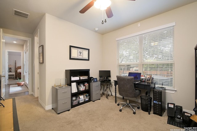 office featuring light colored carpet, ceiling fan, visible vents, and baseboards