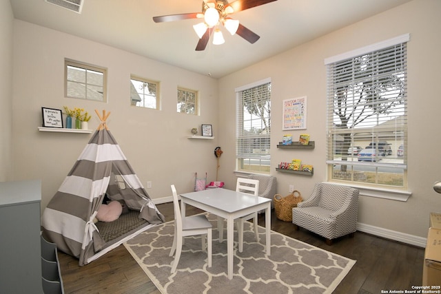 playroom with dark wood-style floors, visible vents, ceiling fan, and baseboards