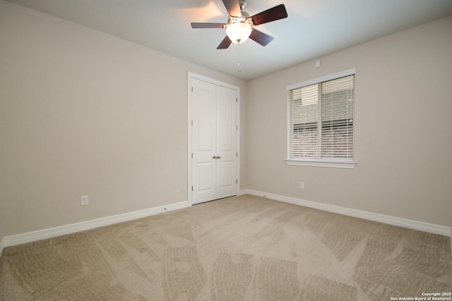 spare room featuring ceiling fan, baseboards, and light colored carpet