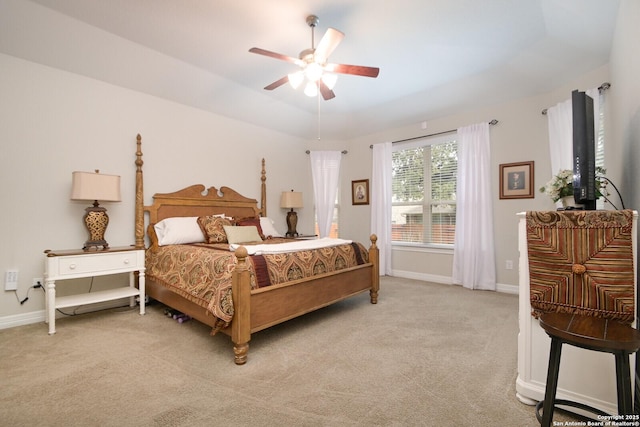 bedroom with a ceiling fan, a tray ceiling, light colored carpet, and baseboards