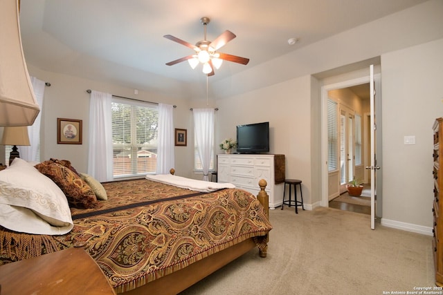 bedroom with a ceiling fan, a raised ceiling, light carpet, and baseboards