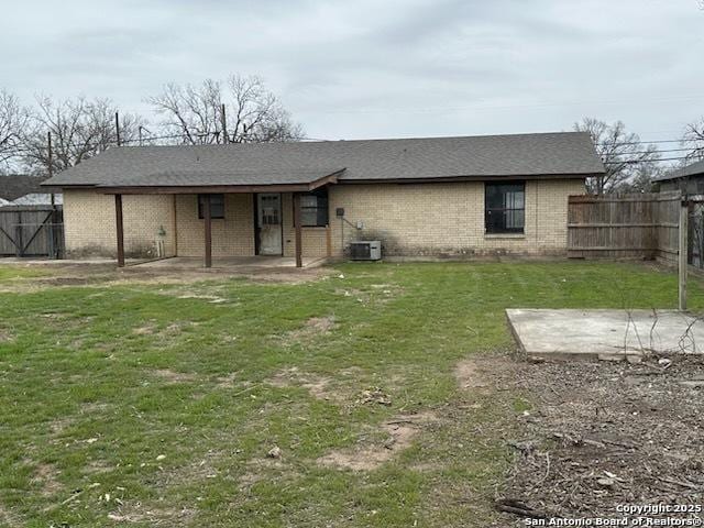 rear view of house with brick siding, central air condition unit, a lawn, a patio area, and a fenced backyard