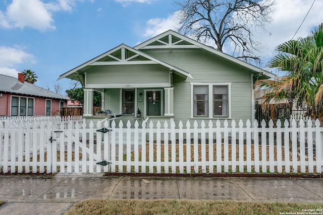 bungalow-style home with a fenced front yard, a gate, and a porch