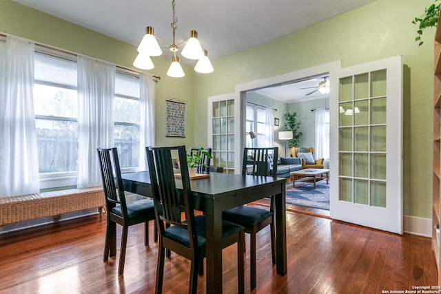 dining room with ceiling fan with notable chandelier, plenty of natural light, and wood finished floors