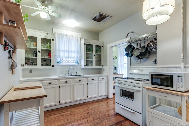 kitchen featuring white appliances, a sink, visible vents, light countertops, and glass insert cabinets