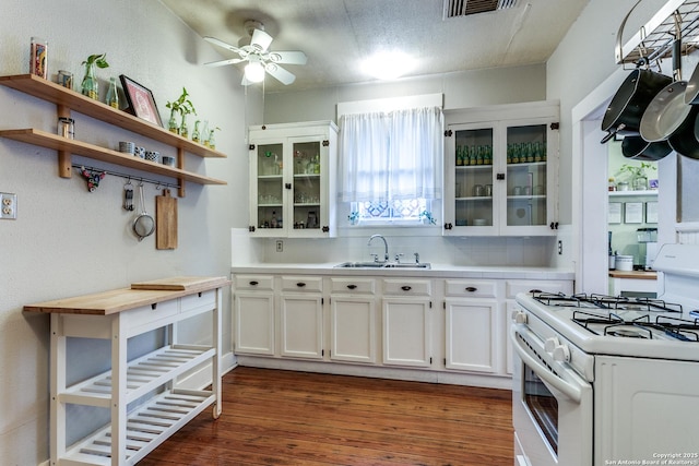 kitchen with white range with gas stovetop, glass insert cabinets, light countertops, white cabinetry, and a sink