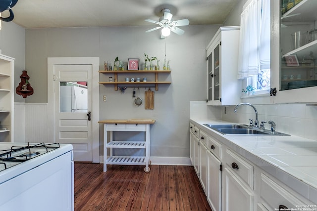 kitchen with freestanding refrigerator, dark wood-style flooring, a sink, and white cabinetry