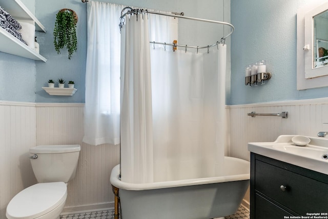 bathroom with a freestanding tub, a wainscoted wall, vanity, and toilet