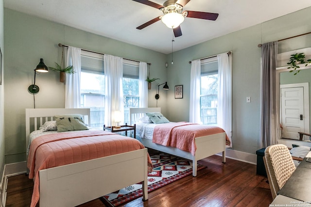 bedroom with dark wood-style floors, a ceiling fan, and baseboards