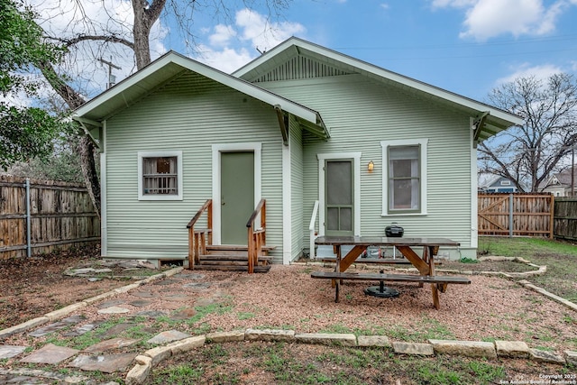 rear view of house featuring entry steps and a fenced backyard