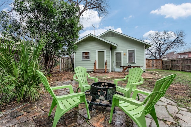 back of house featuring a fenced backyard and a fire pit