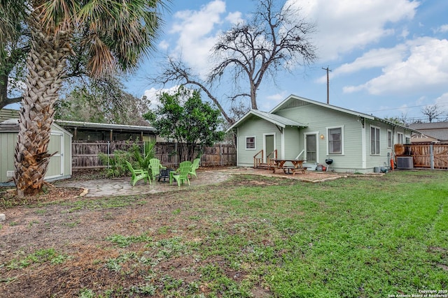 rear view of property featuring a fenced backyard, central air condition unit, a lawn, a shed, and a patio area