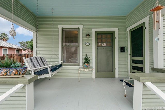 property entrance with fence and a porch