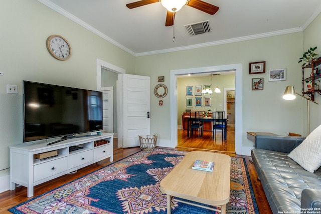 living area with visible vents, wood finished floors, and ornamental molding