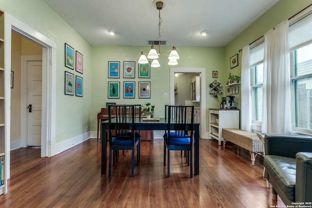 dining area with dark wood-style flooring, visible vents, baseboards, and an inviting chandelier