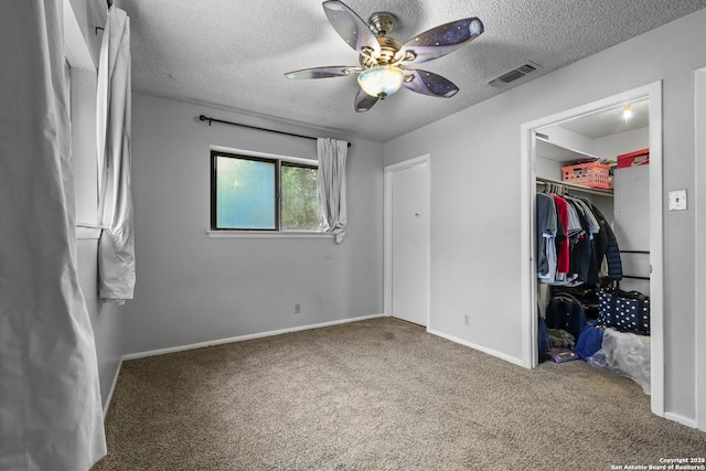 unfurnished bedroom with a textured ceiling, visible vents, a spacious closet, a closet, and carpet