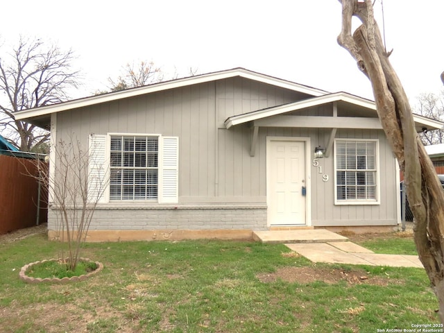 view of front of home featuring fence, a front lawn, and brick siding