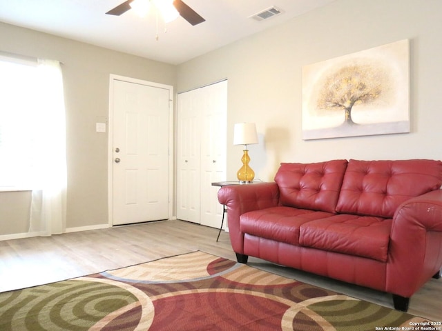 living area with baseboards, ceiling fan, visible vents, and wood finished floors