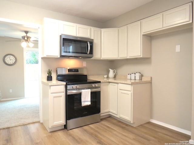 kitchen featuring stainless steel appliances, white cabinetry, light wood-style flooring, and baseboards