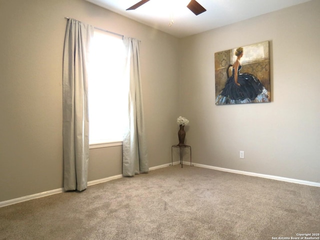 carpeted empty room featuring a ceiling fan and baseboards