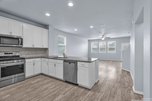 kitchen with appliances with stainless steel finishes, open floor plan, white cabinetry, and dark stone countertops