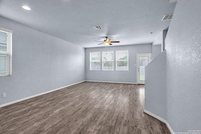 unfurnished living room with wood finished floors, visible vents, and baseboards