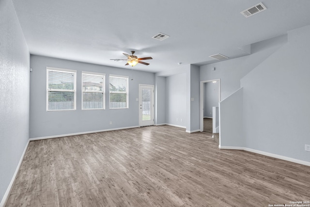 unfurnished living room with baseboards, ceiling fan, visible vents, and wood finished floors