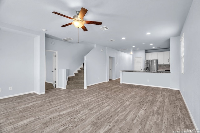 unfurnished living room with light wood finished floors, stairs, and visible vents