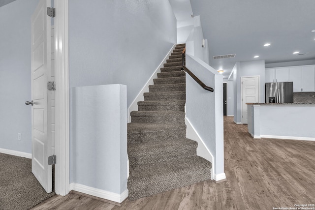 stairway featuring recessed lighting, visible vents, baseboards, and wood finished floors