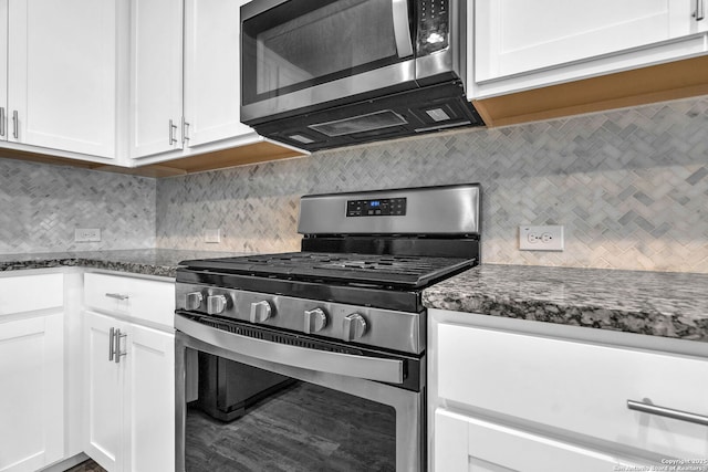 kitchen with white cabinetry, appliances with stainless steel finishes, and dark stone countertops