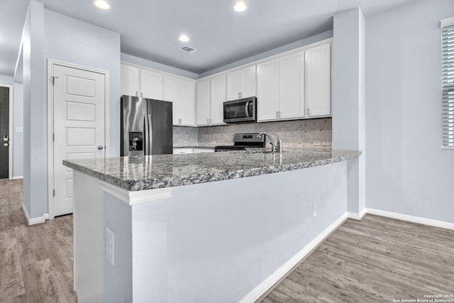 kitchen with visible vents, light wood-style flooring, a peninsula, stainless steel appliances, and white cabinetry