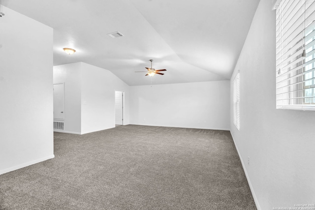 empty room featuring lofted ceiling, carpet, visible vents, and ceiling fan