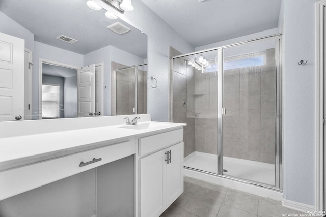 full bath with vanity, a shower stall, visible vents, and tile patterned floors