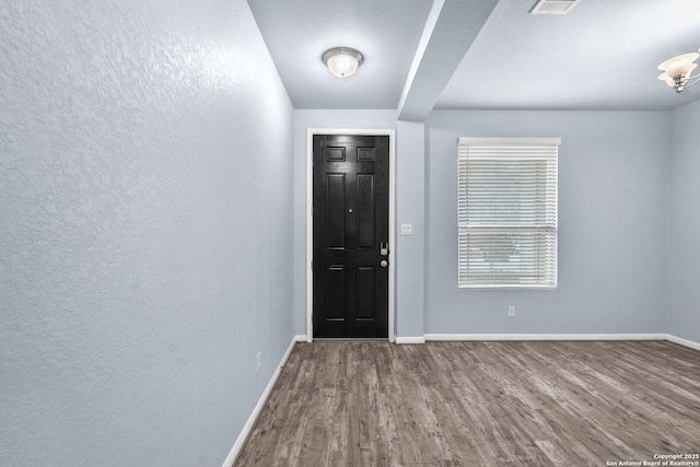 entrance foyer with a textured wall, wood finished floors, and baseboards