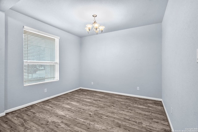 unfurnished room with baseboards, a chandelier, and dark wood-type flooring