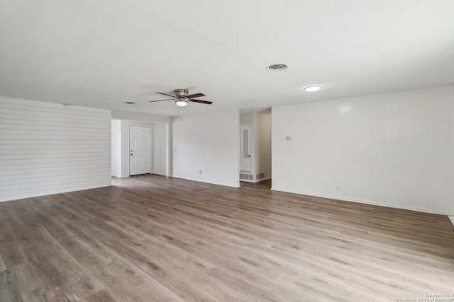 empty room featuring ceiling fan, light wood finished floors, and visible vents