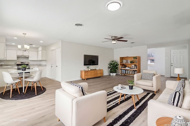 living area with recessed lighting, visible vents, baseboards, light wood-style floors, and ceiling fan with notable chandelier