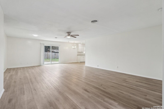 empty room featuring light wood-style floors, visible vents, baseboards, and a ceiling fan